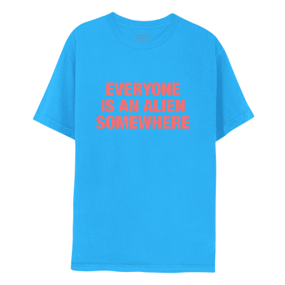 Front: This is Chris’s shirt. Fabric is a very vibrant blue. EVERYONE IS AN ALIEN SOMEWHERE is salmon pink. The text is large and bold, in 3 lines: EVERYONE, IS AN ALIEN, SOMEWHERE.  