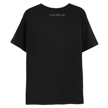 2: Back: The shirt is black. COLDPLAY is printed in white, just below the neckline. MUSIC OF THE SPHERES is written on the right sleeve. The band name is in a classic, elegant font, with small decorative lines or strokes at the ends of the letters