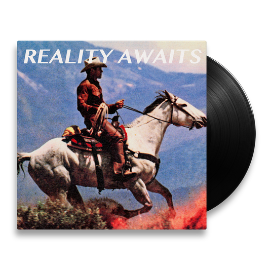 The Strokes Reality Awaits Vinyl record with a cowboy on a horse in front of a mountainous background. The Black Colored Vinyl is poking out of the packaging to showcase the color variant. 