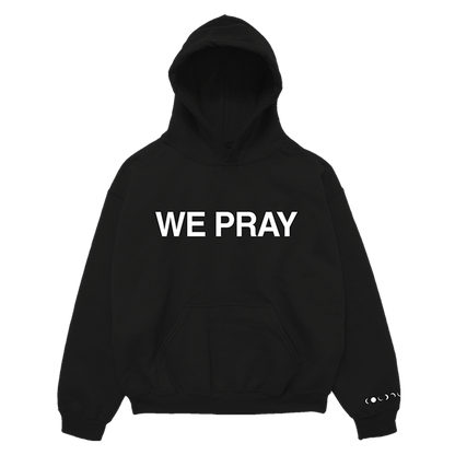 Front: WE PRAY is printed in large, white, bold letters across the chest of a black hoodie. Coldplay is spelled out in white phases of the moon on the wrist of the left sleeve. It also has a large center pocket at the waist.